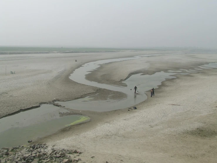 three people walking along the side of a river