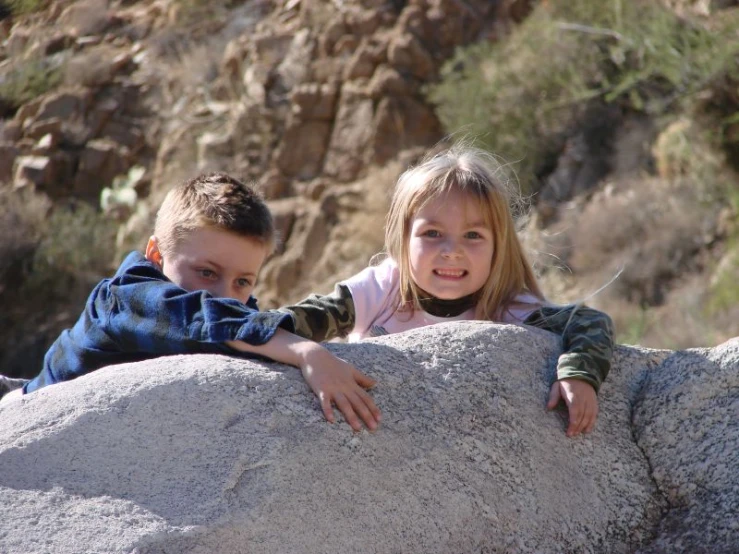 a couple of s climbing on top of a boulder