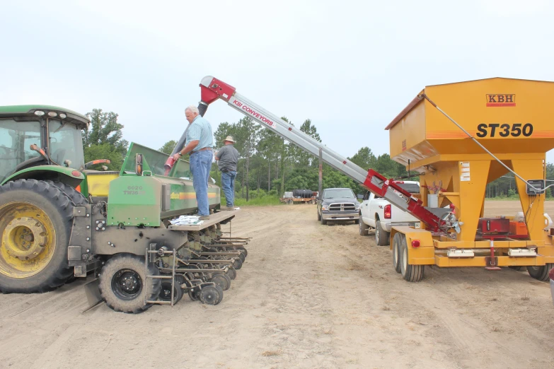 a man in a light blue shirt stands on top of a construction machine