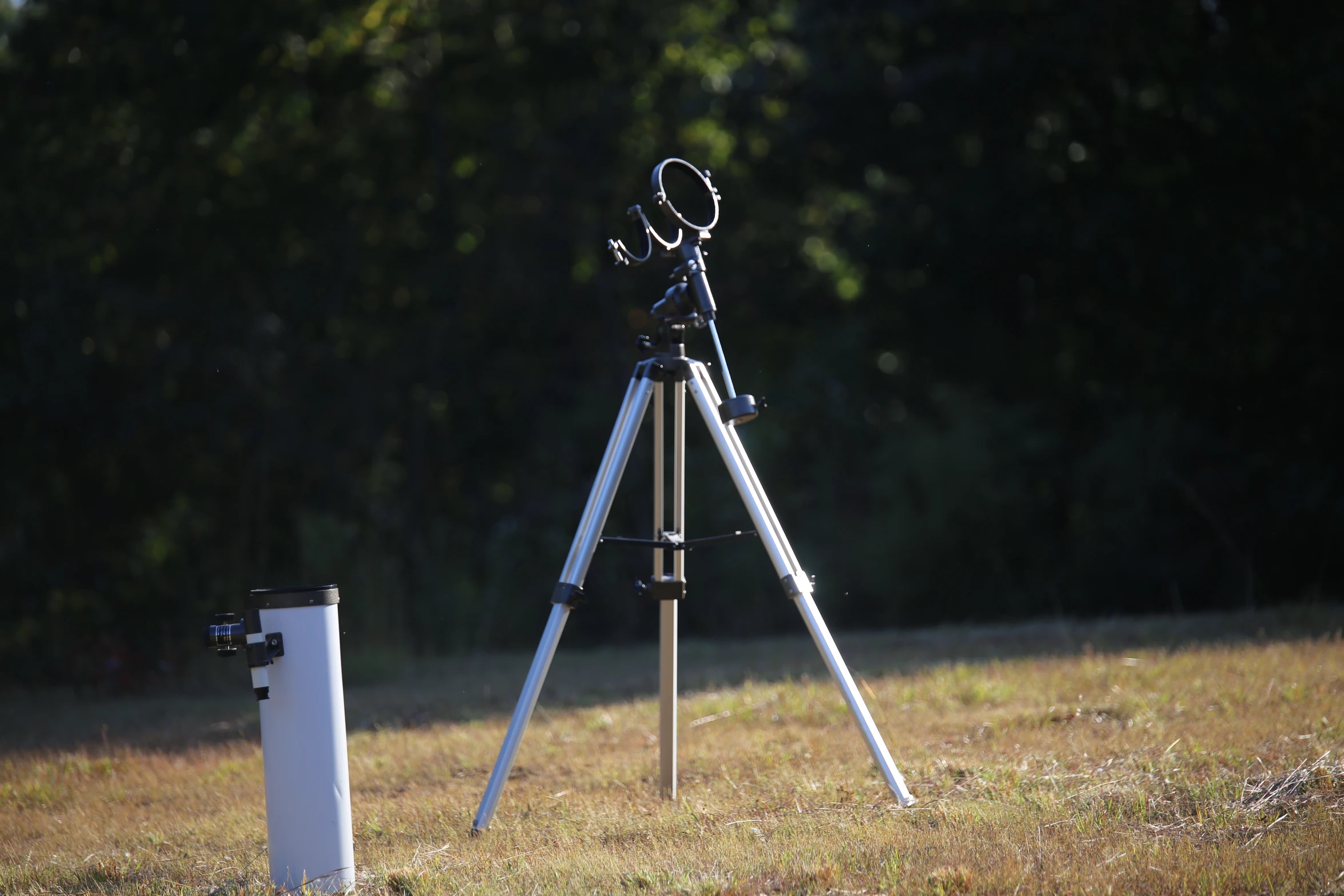 an antique telescope and tripod stand in a field