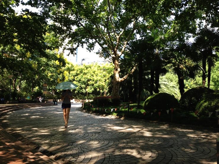 woman walking down a walkway with an umbrella in hand