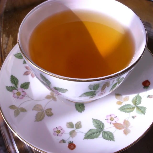 a cup and saucer on a saucer with tea in it