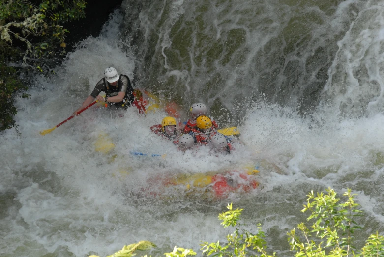 two people on rafts and one man paddling down waterfall