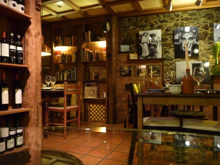 a rustic bar with a stone wall and shelves filled with bottles of wine