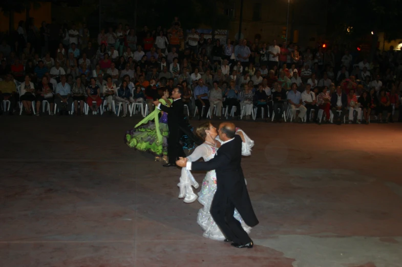 a couple dancing on a cement stage with an audience