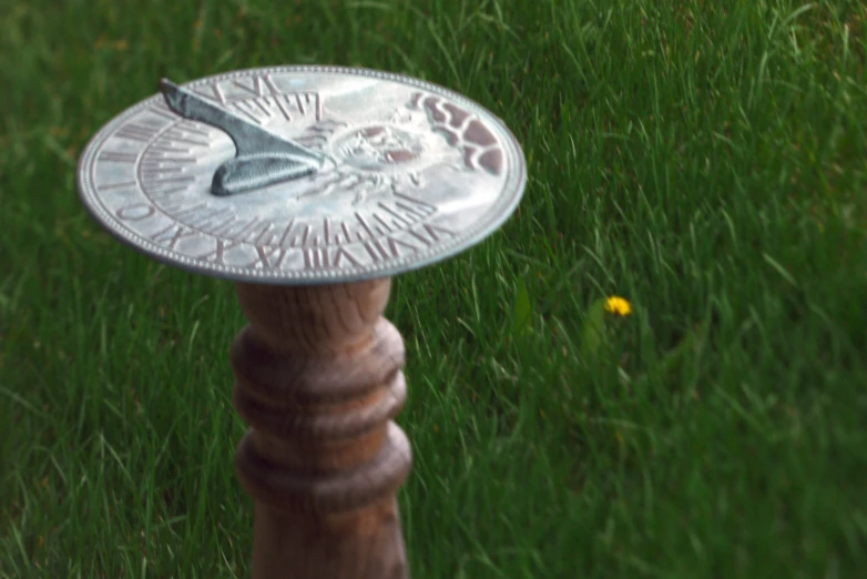 a metal bird bath sits in a green lawn