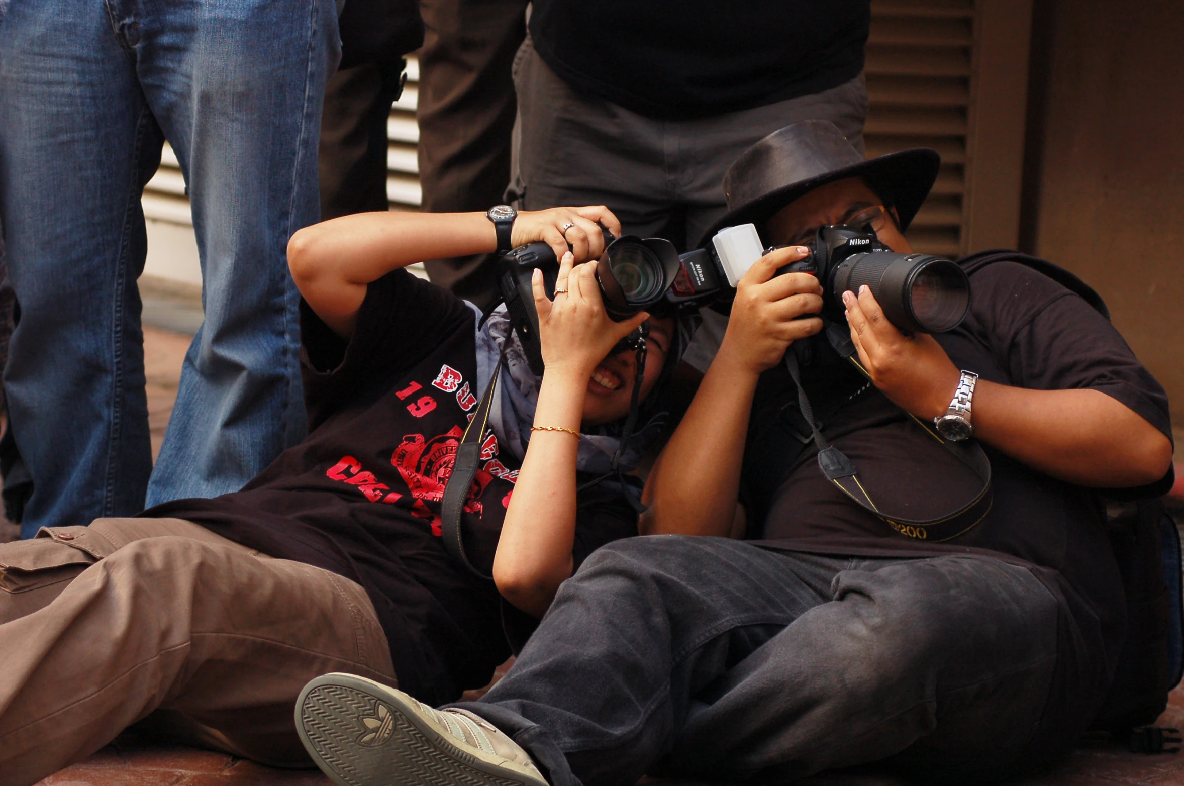 two people laying next to each other while one holds his camera