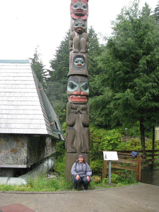 a man is posing in front of a tall totema