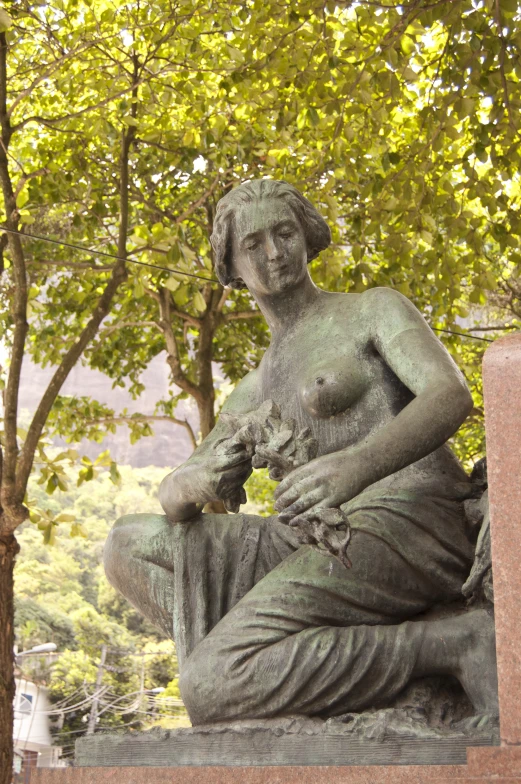 a statue sitting next to some trees with the sky in the background