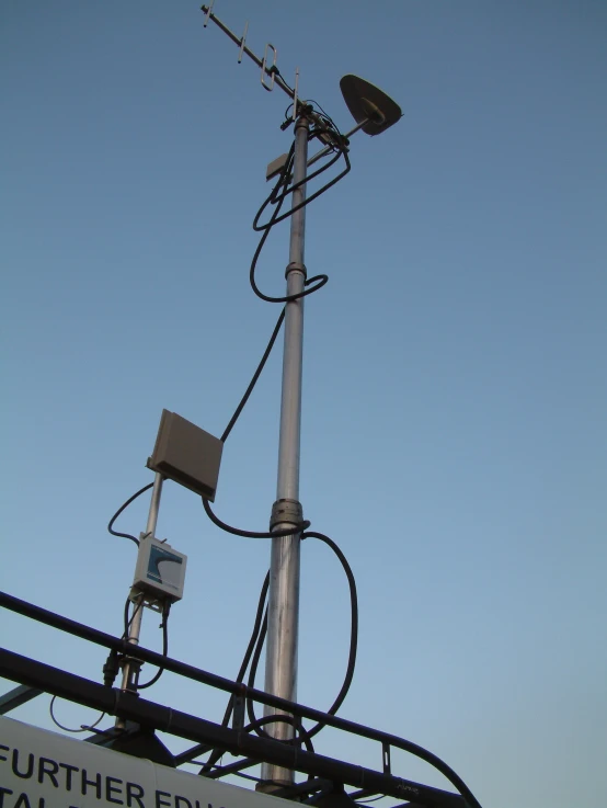 a metal pole is attached to a radio tower with two satellite dishes attached