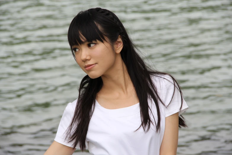 a girl standing by the water with long black hair