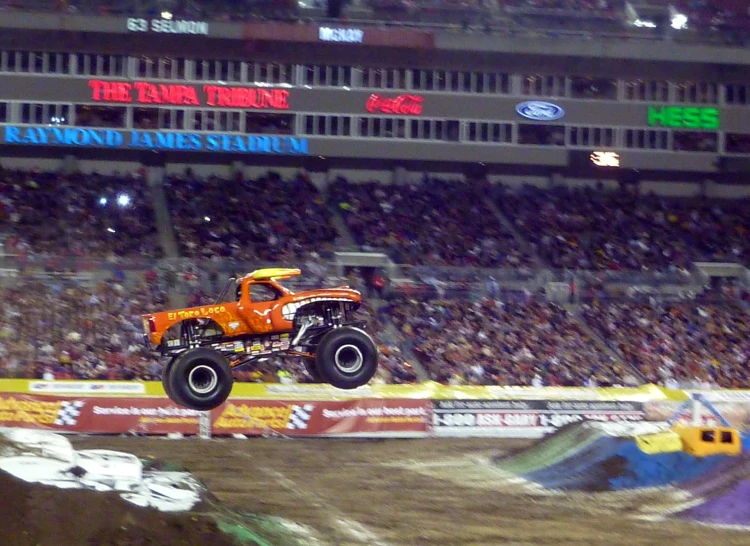 a monster truck going down a track in front of an audience