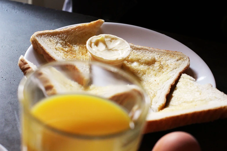 a plate of bread and eggs with an orange next to it