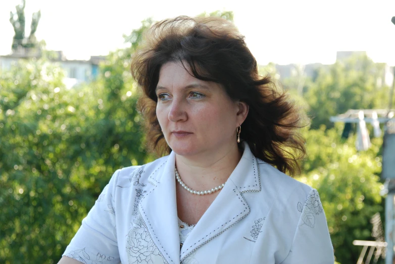 a woman sitting on a patio chair in front of trees