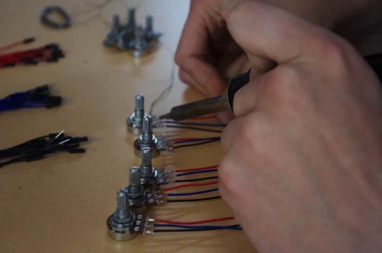 two hands attaching various wires to a project