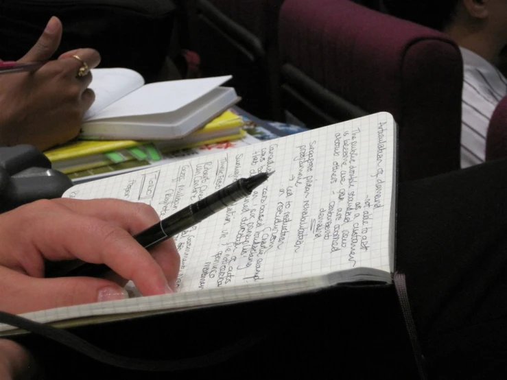 a person's hand writing on top of a book