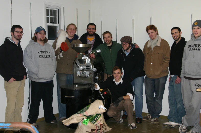 several men and women posing around an old fashioned machine