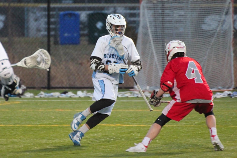 a man holding a lacrosse stick in front of a person holding a ball