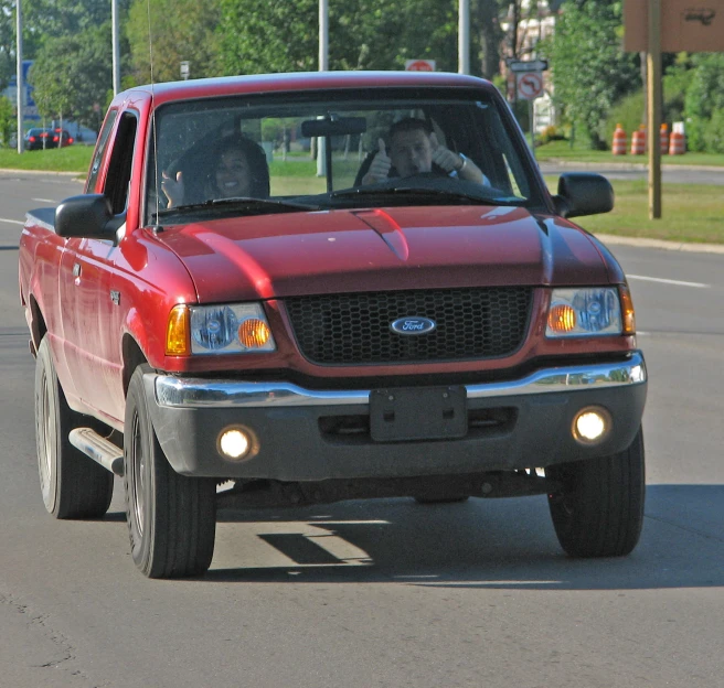 a red pickup truck driving down the street