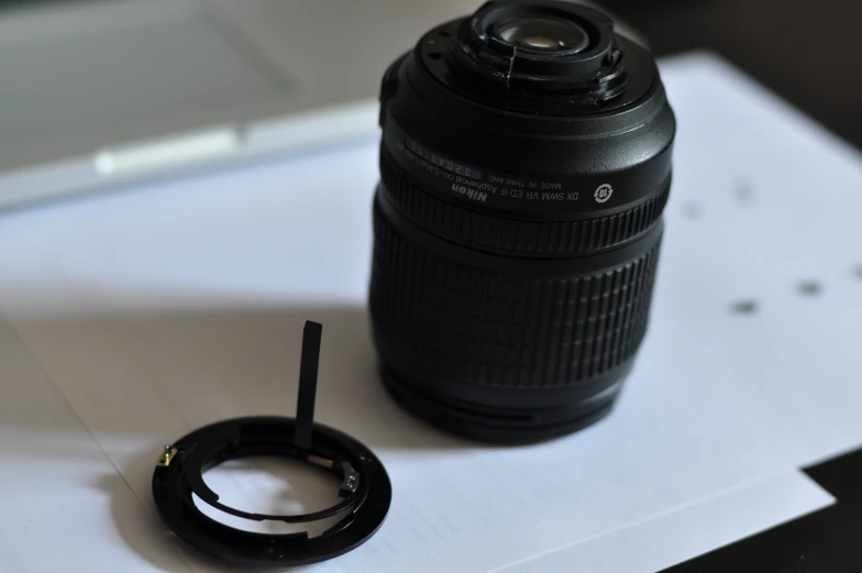 a zoom lens sits on a piece of paper next to a camera hood