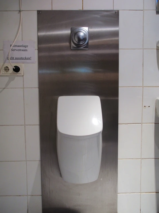 a white urinal in a bathroom next to a wall