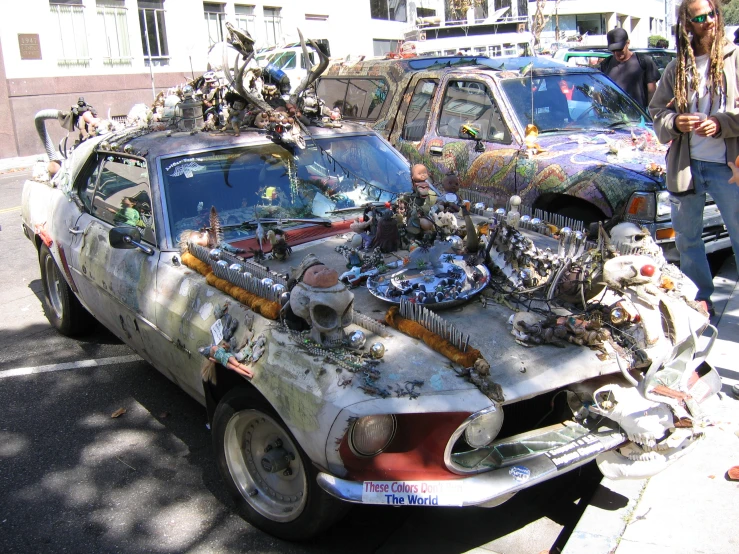 the old car with some decorations on the hood sits parked next to an older model