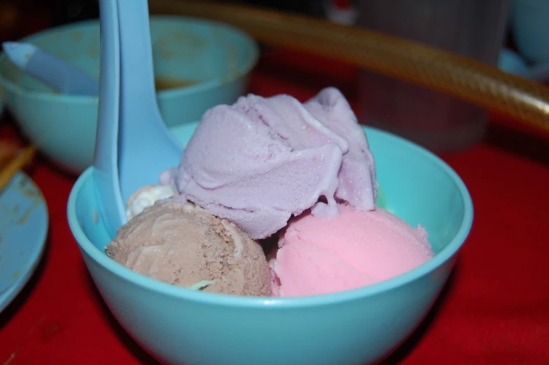 some pink and purple ice cream in a blue bowl with spoons