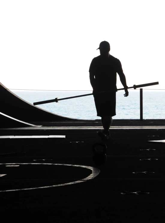 a man walking along a boardwalk next to a body of water