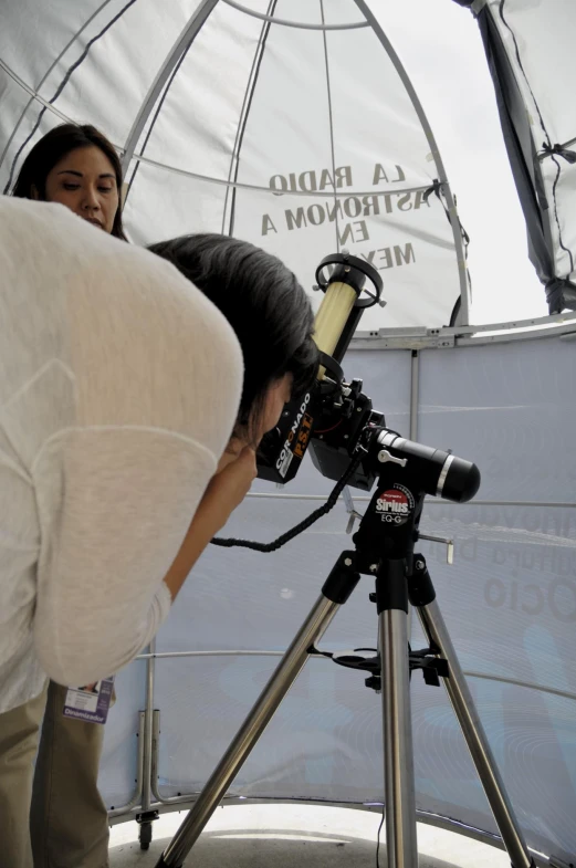 a woman leaning down to take pictures with her computer on the tripod