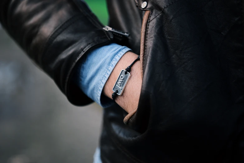 the man wears a watch while holding a leather jacket