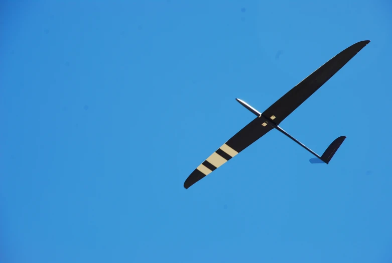 a glider plane is seen against a bright blue sky