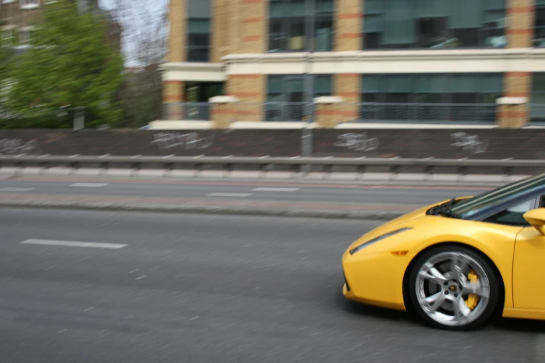 a yellow sports car is driving down the street