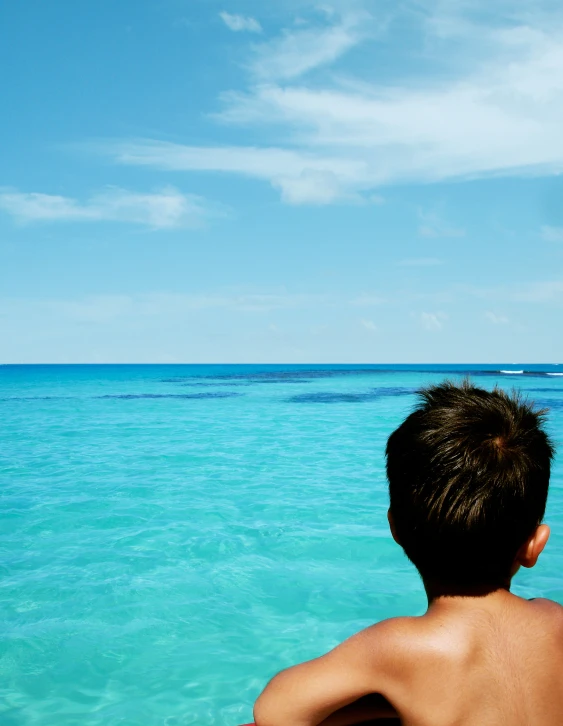 the boy is sitting in the boat looking at the water