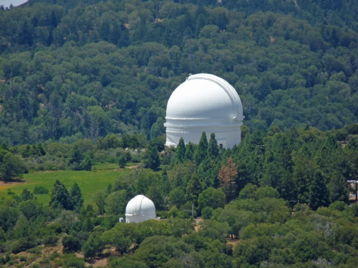 two large white domes on a hill near some trees