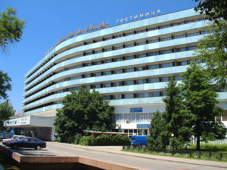 a very tall building next to the street with lots of cars parked