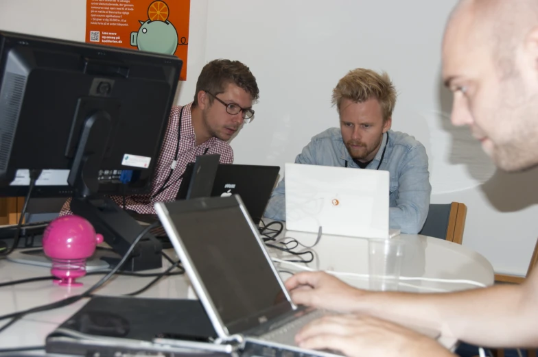 three men look at soing on their laptops