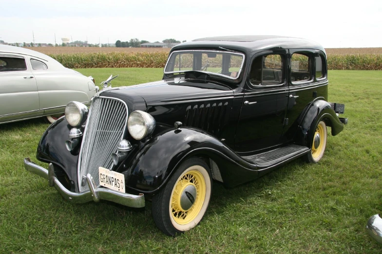 an old black car sitting in the grass