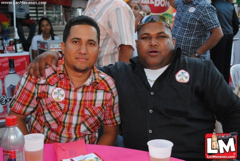 two men pose for a picture in front of food