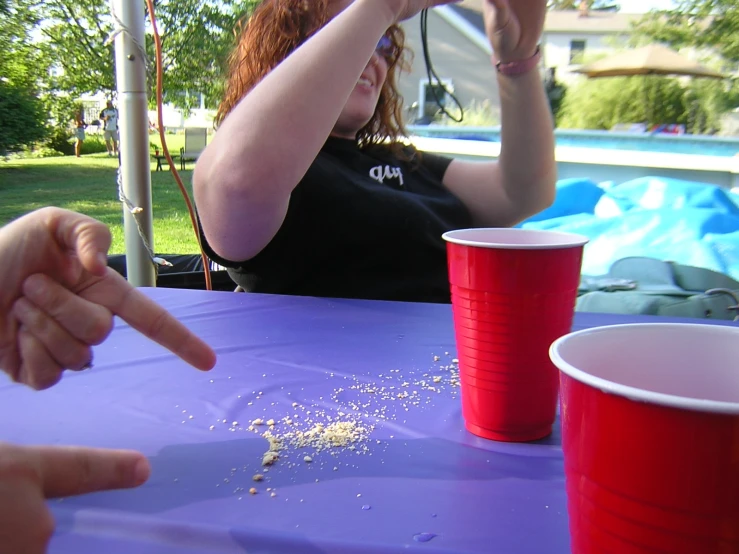 two women sitting at a table with one pointing