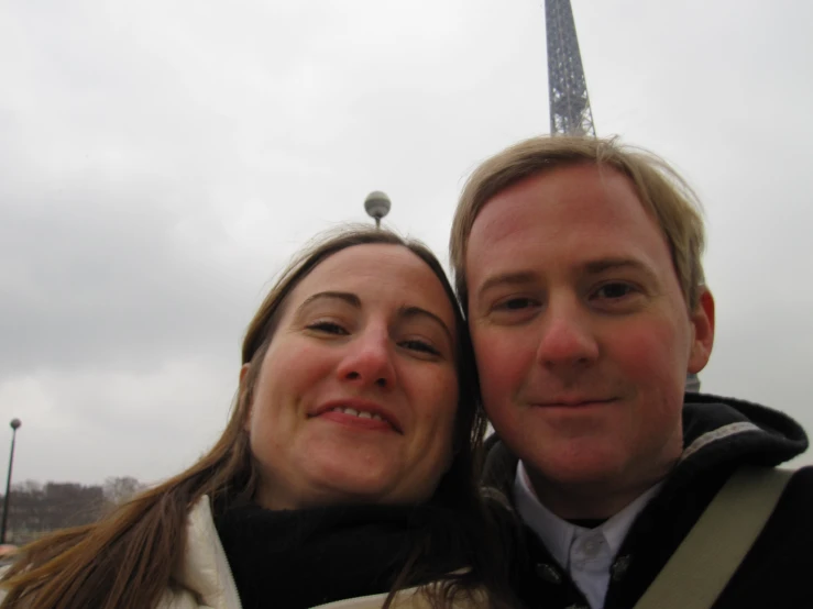 a man and a woman pose together in front of the eiffel tower