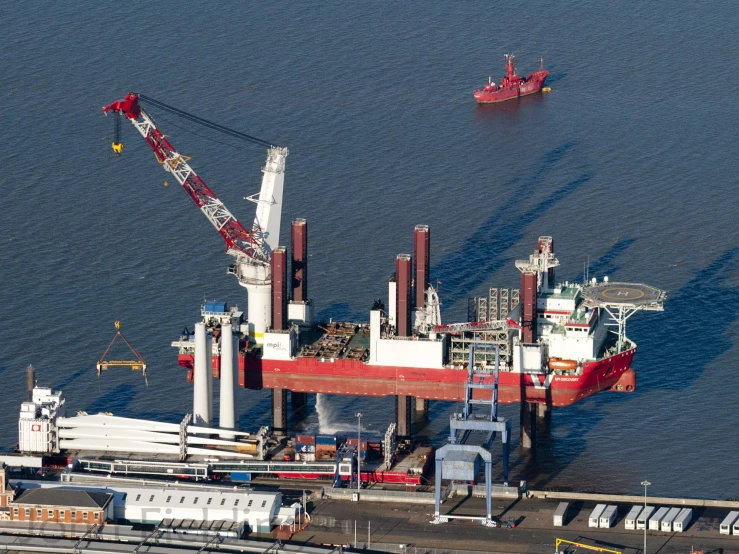 two red ships on water in front of docks and boats