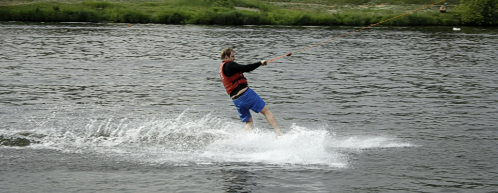 man waterskiing on a body of water with a rope
