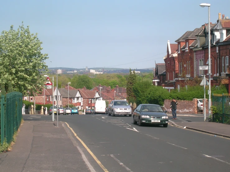 a road full of vehicles, with brick homes in the background