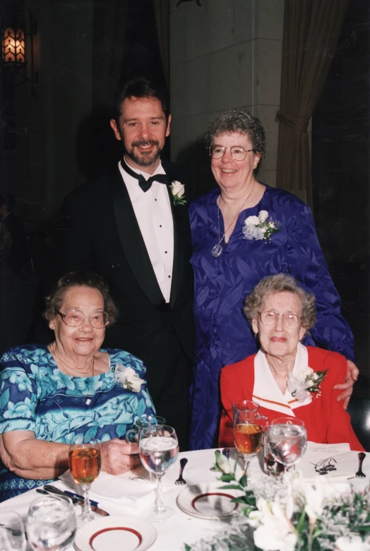 two women and an elderly man in formal attire sitting at a table