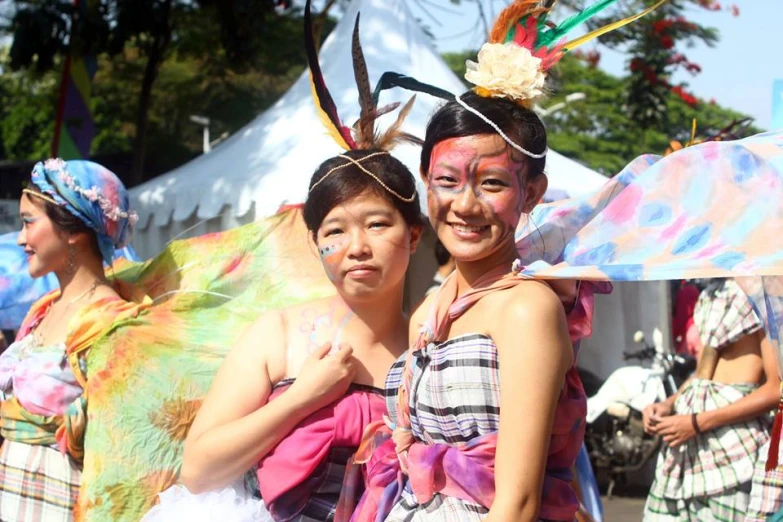 two women dressed in colorful clothes and masks, smiling for the camera