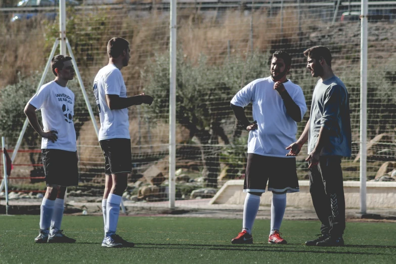 three soccer players stand together during practice on the field