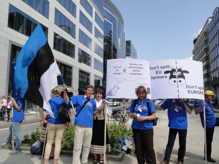 some people with blue shirts holding signs outside