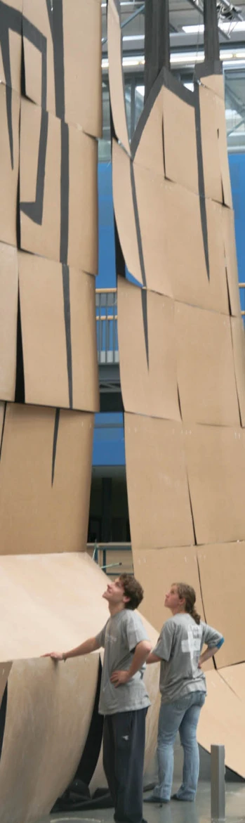 two women stand in front of cardboard like structures