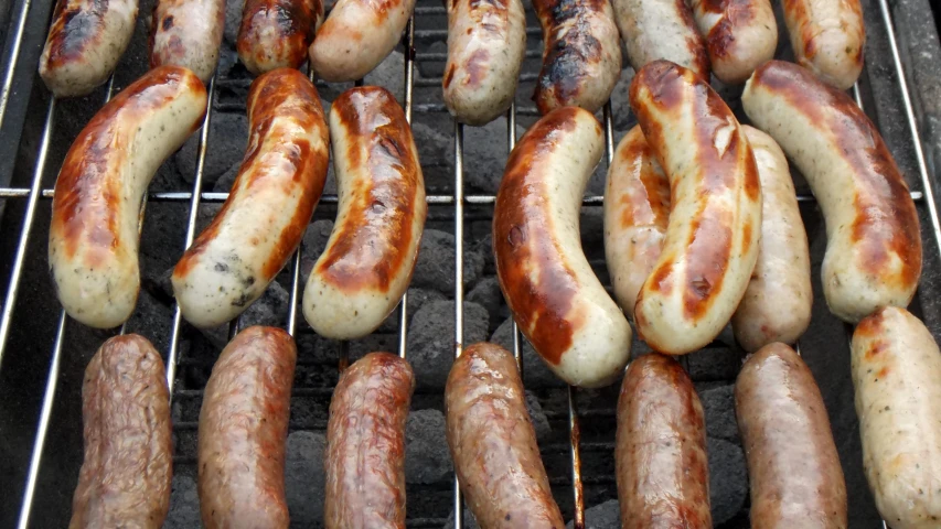 several sausages and twurst are on a bbq grill