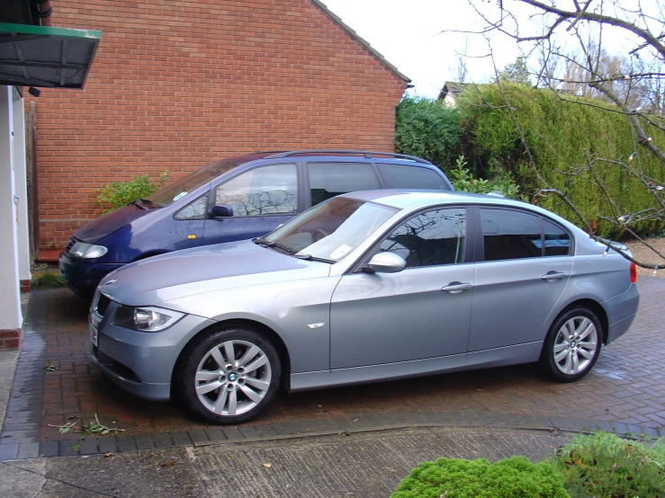 the silver bmw is parked outside a house